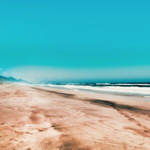 A pristine sandy beach with turquoise skies and gentle waves, perfect for travel enthusiasts.
